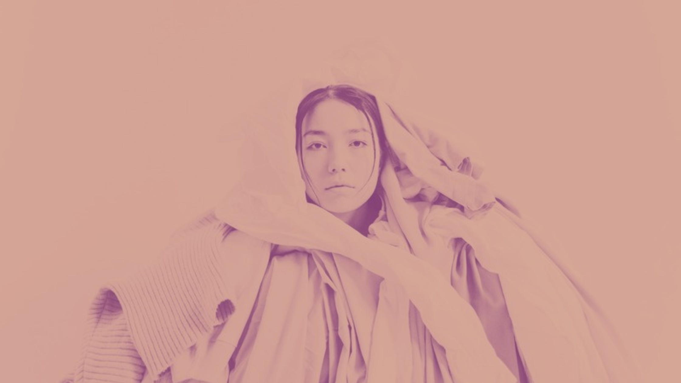 Layered clothing arranged on a soft neutral background, representing dressing for unpredictable seasons